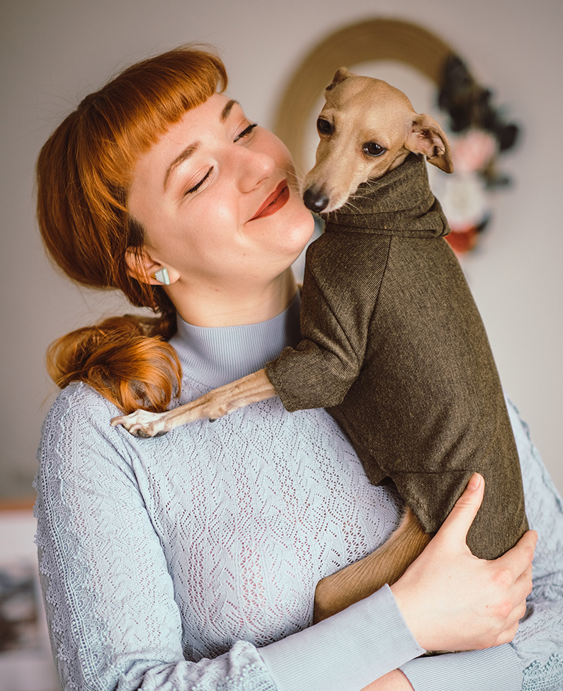 A happy woman holding her greyhound